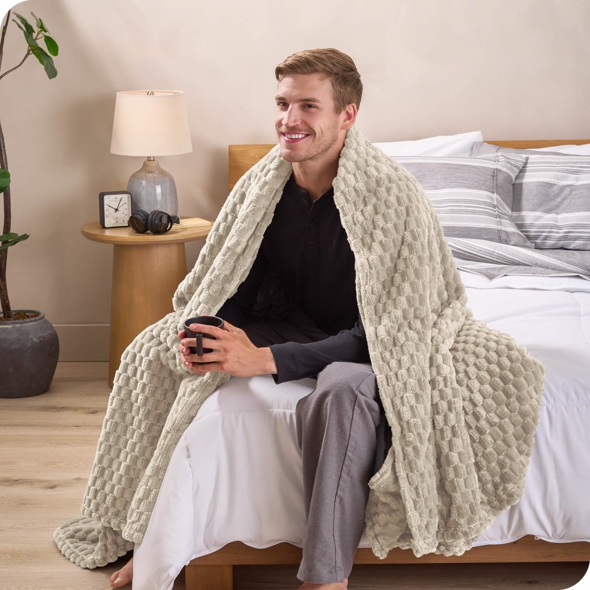 A man sitting on a bed wrapped in a microplush blanket