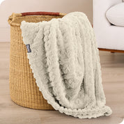 A sherpa blanket is hanging over the edge of a woven hamper
