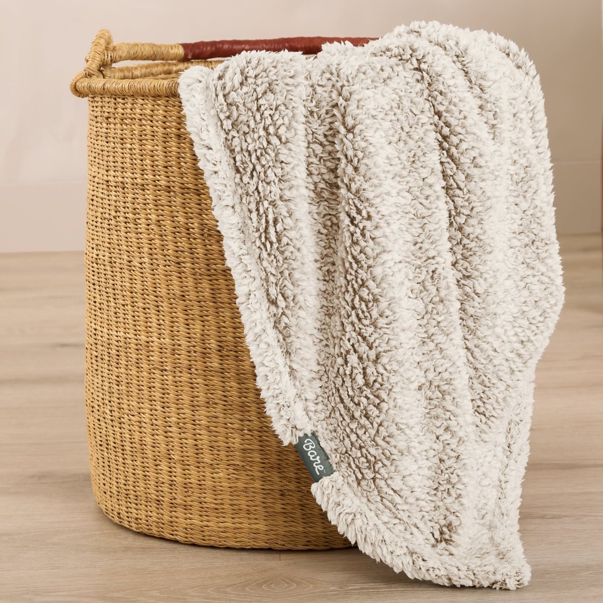Textured blanket draped over a wicker basket on a wooden surface