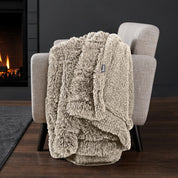 Sherpa blanket draped over an armchair in front of a fireplace.