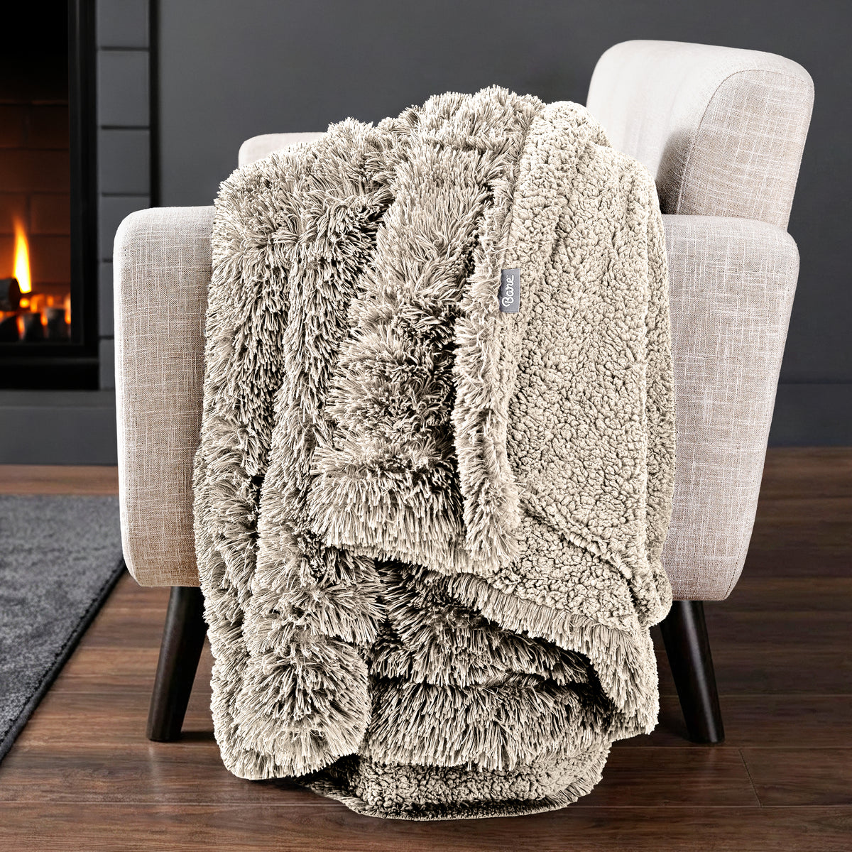 Sherpa blanket draped over an armchair in front of a fireplace.