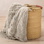 A blanket hanging over the edge of a wicker basket
