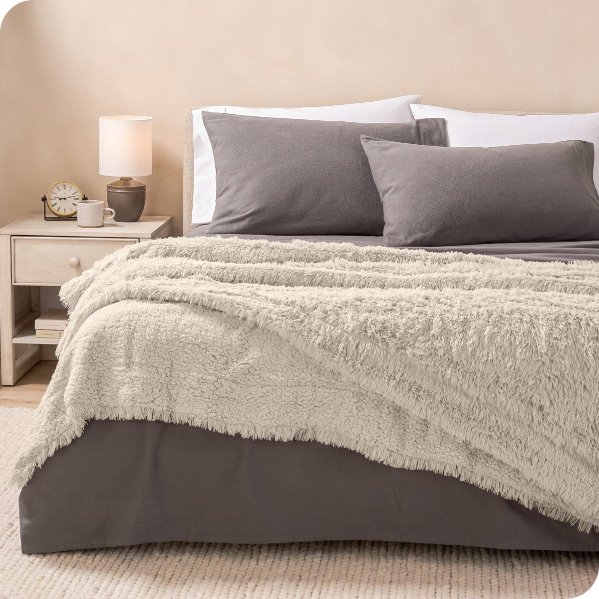 A shaggy faux fur blanket on the end of a bed
