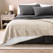 Bed with grey sheets and a sherpa blanket