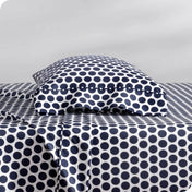 Two pillows with pillowcases on them stacked on a bed