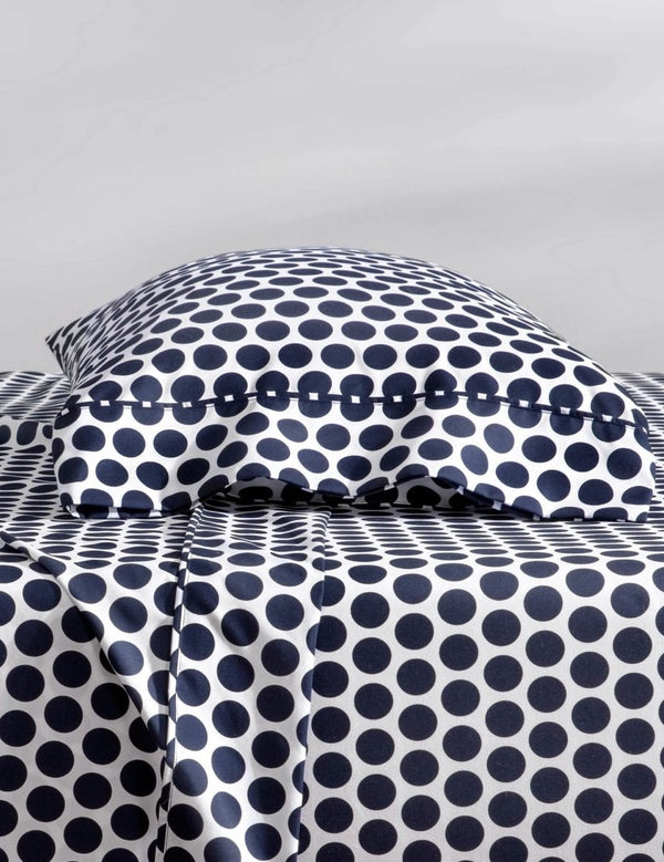 Two pillows with pillowcases on them stacked on a bed