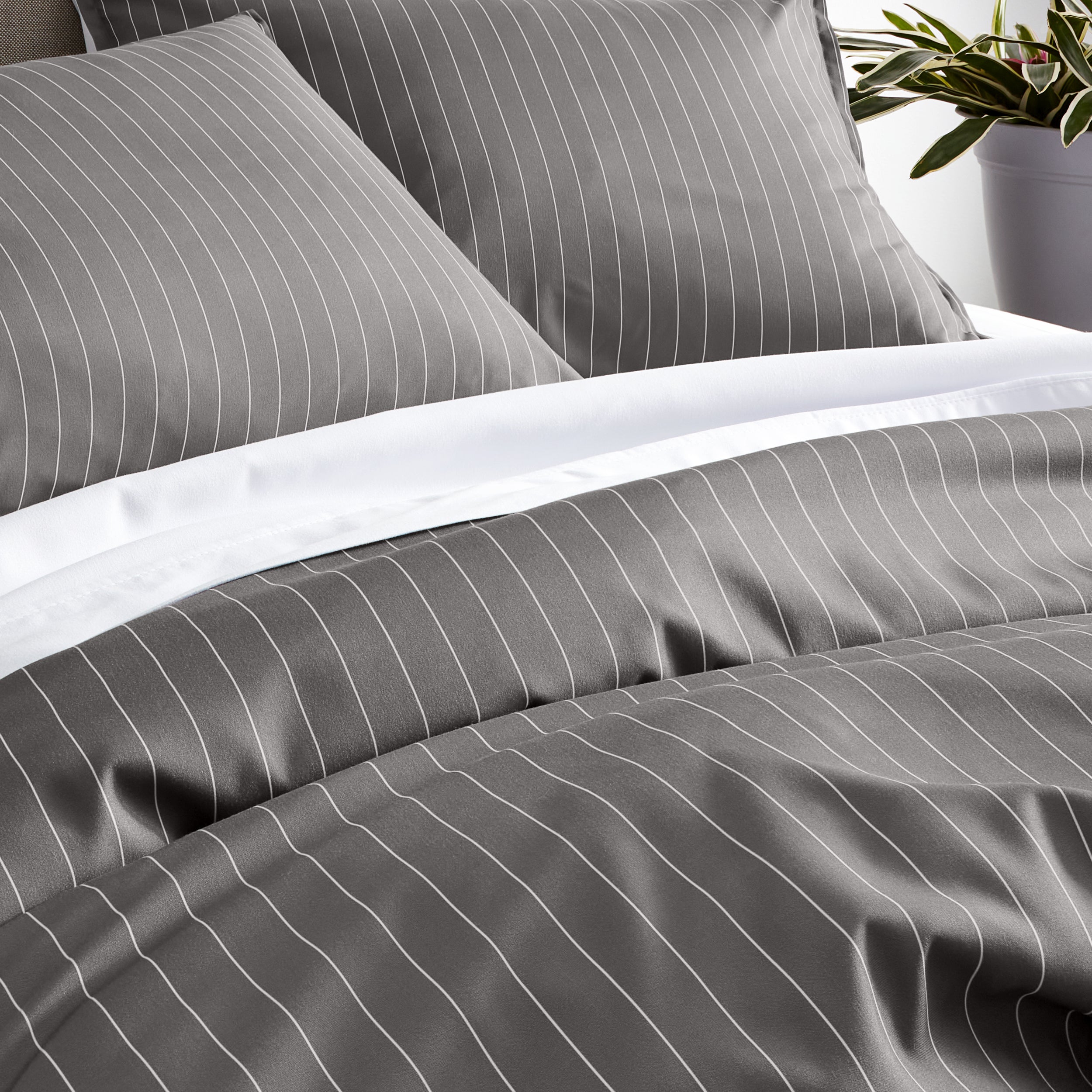Gray bedding set with thin white vertical pinstripes, including a duvet cover and two pillow shams