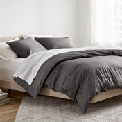 A neatly made bed in a bright bedroom setting, featuring a dark gray and white striped duvet cover.