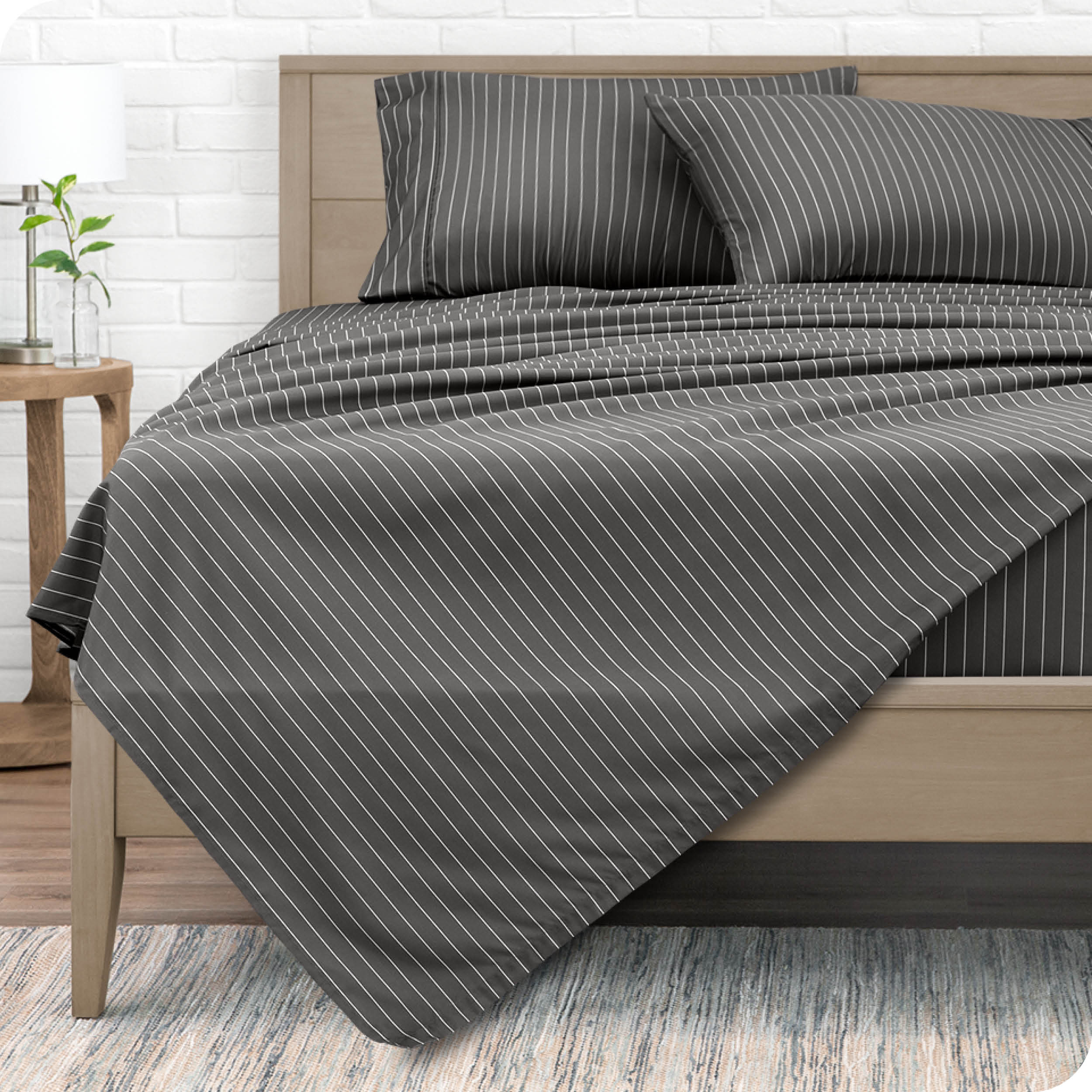 A modern bed with a microfiber sheet set on it.