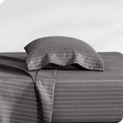 Two pillows with pillowcases on them stacked on a bed