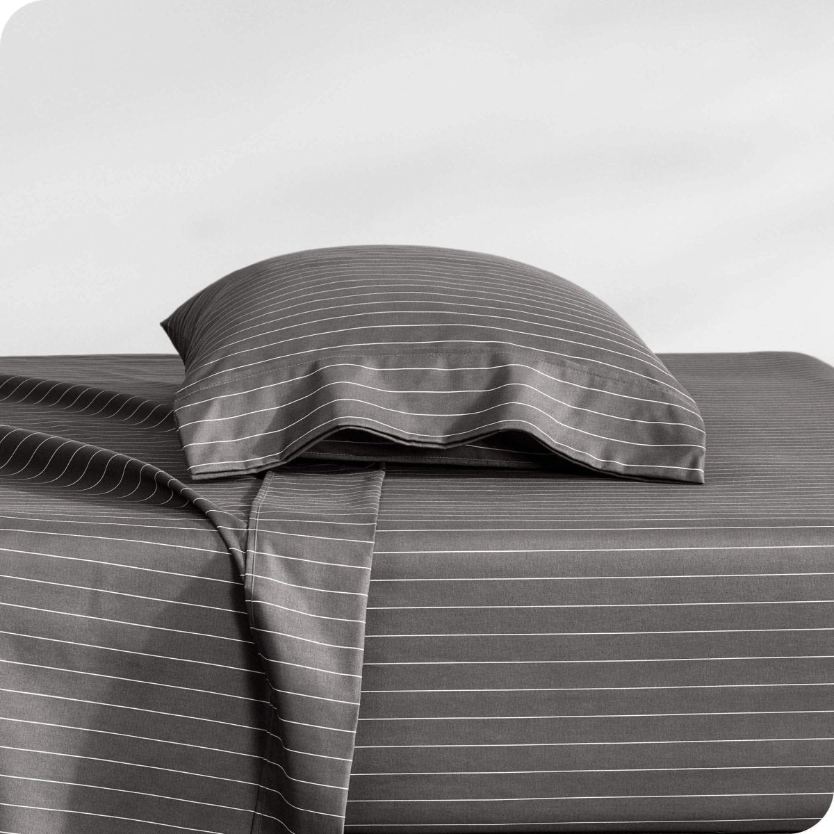 Two pillows with pillowcases on them stacked on a bed
