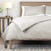 Neatly made bed with striped bedding in a bedroom setting.