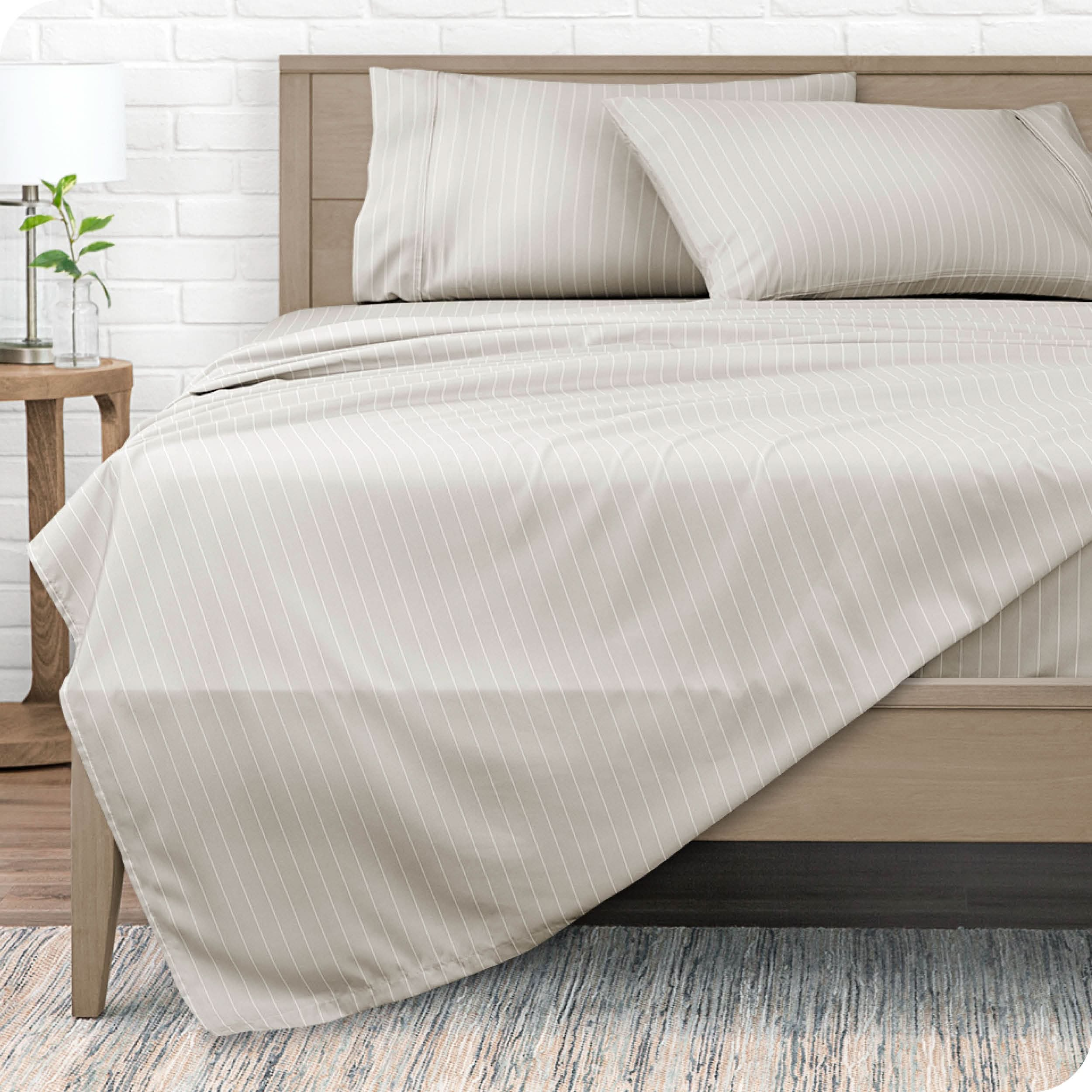 A modern bed with a microfiber sheet set on it.