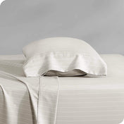 Two pillows with pillowcases on them stacked on a bed