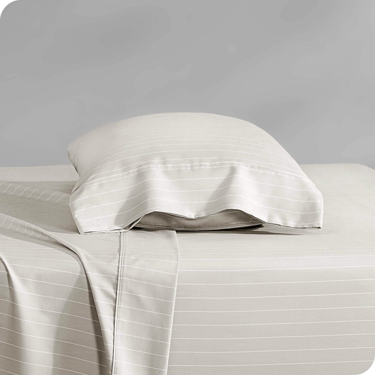 Two pillows with pillowcases on them stacked on a bed