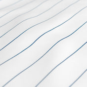 A close-up of white fabric with thin blue pinstripes