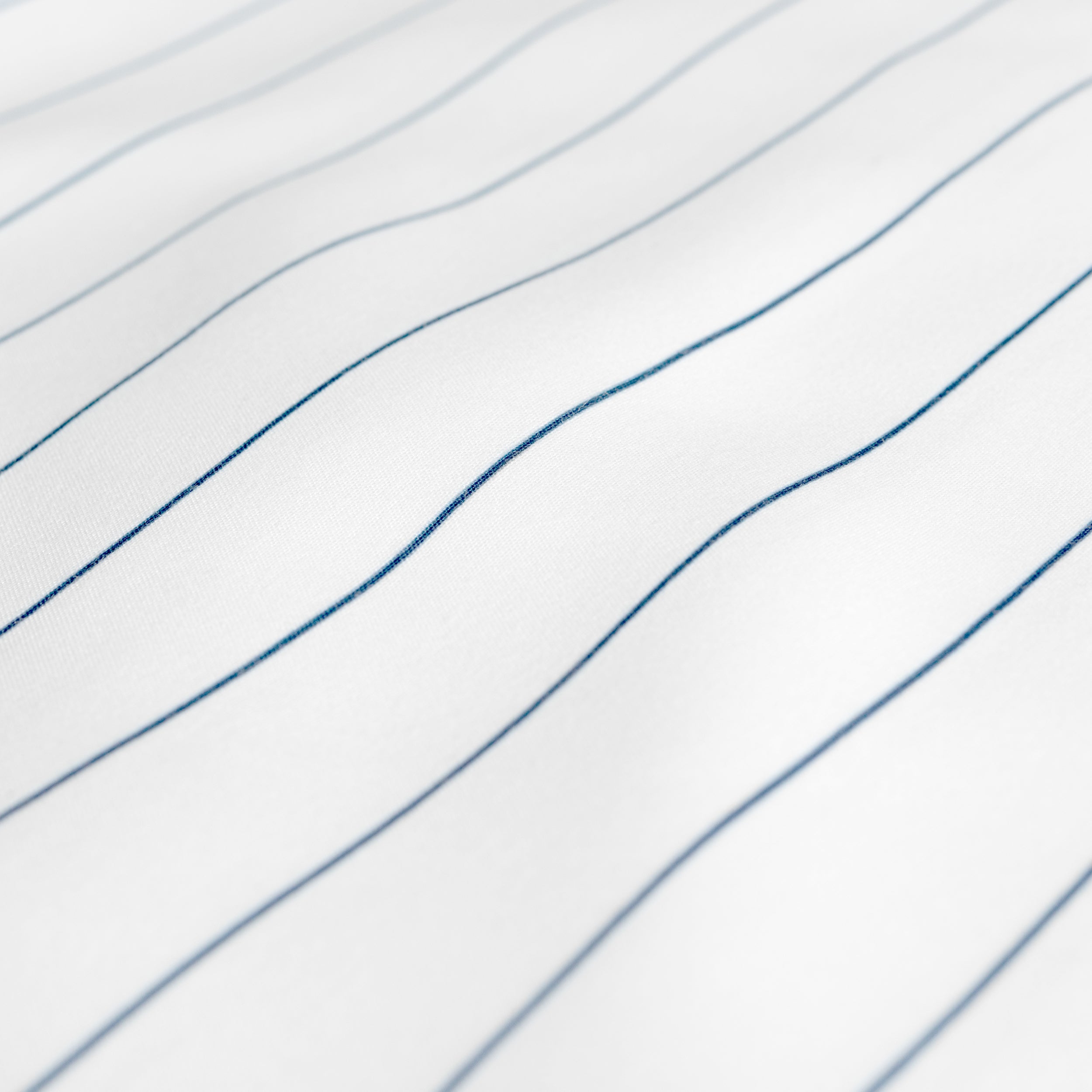 A close-up of white fabric with thin blue pinstripes