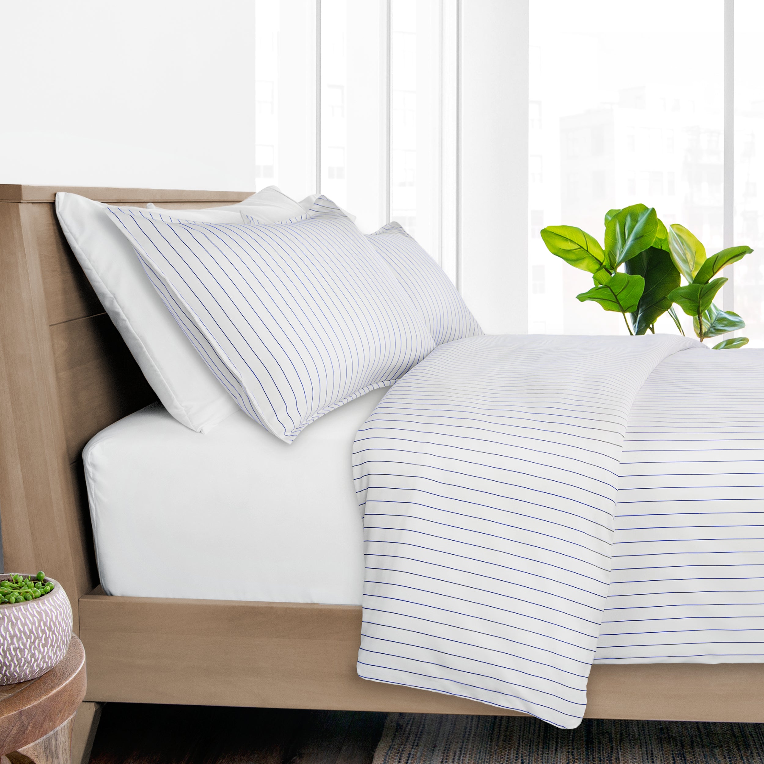 A neatly made bed with white bedding featuring thin blue vertical stripes