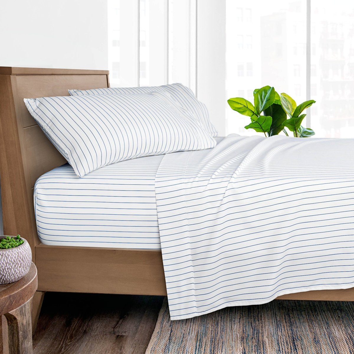 White bed sheet set with thin blue stripes, styled on a wooden bed frame