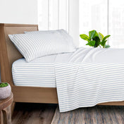 White bed sheet set with thin blue stripes, styled on a wooden bed frame