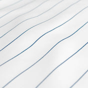 A close-up of white fabric with thin, blue pinstripes