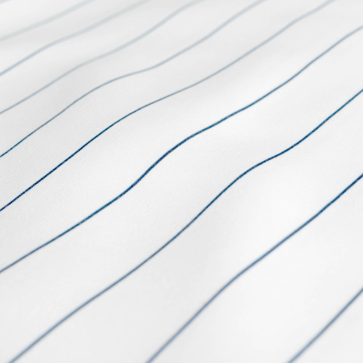 A close-up of white fabric with thin, blue pinstripes