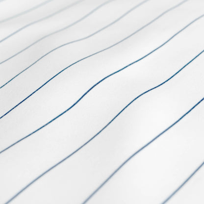 A close-up of white fabric with thin, blue pinstripes
