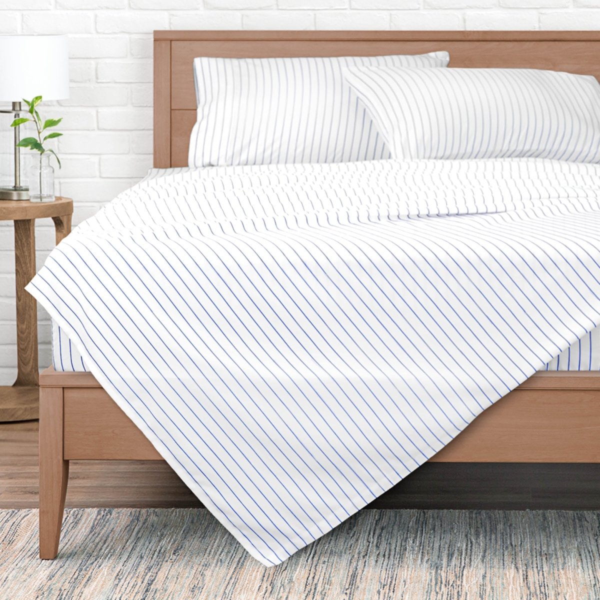 White bedding with thin blue vertical pinstripes, styled on a wooden bed frame