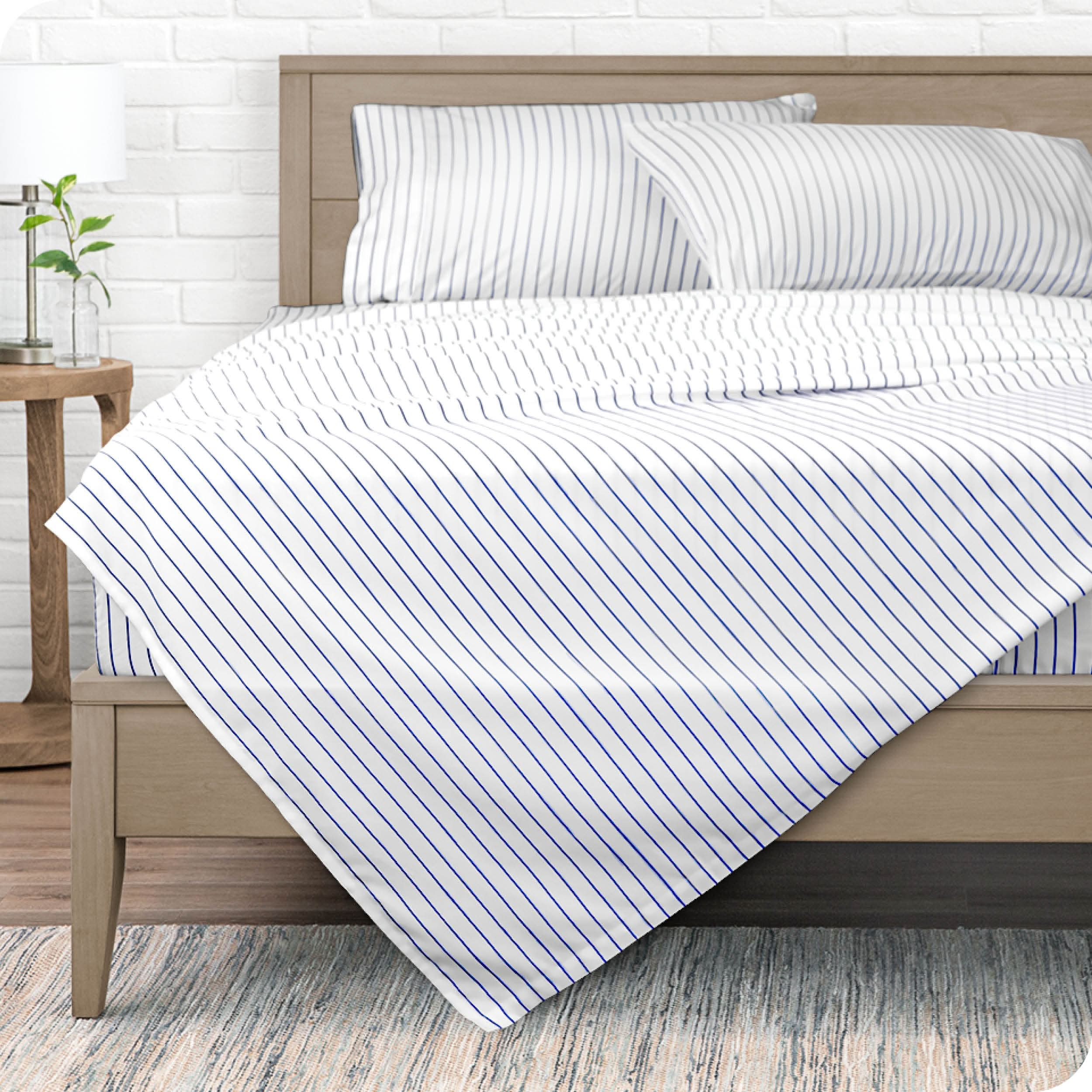 A modern bed with a microfiber sheet set on it.