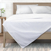 A modern bed with a microfiber sheet set on it.