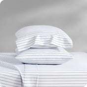 Two pillows with pillowcases on them stacked on a bed