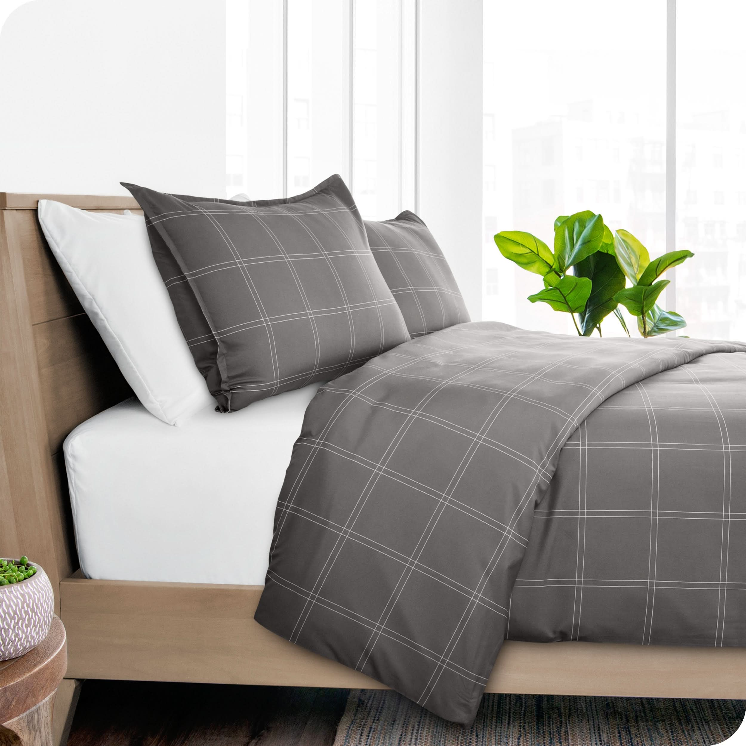 Angled view of bed showing a printed duvet cover draped over side of bed and included pillow shams