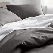 Gray and white plaid bedding set on a bed with pillows.