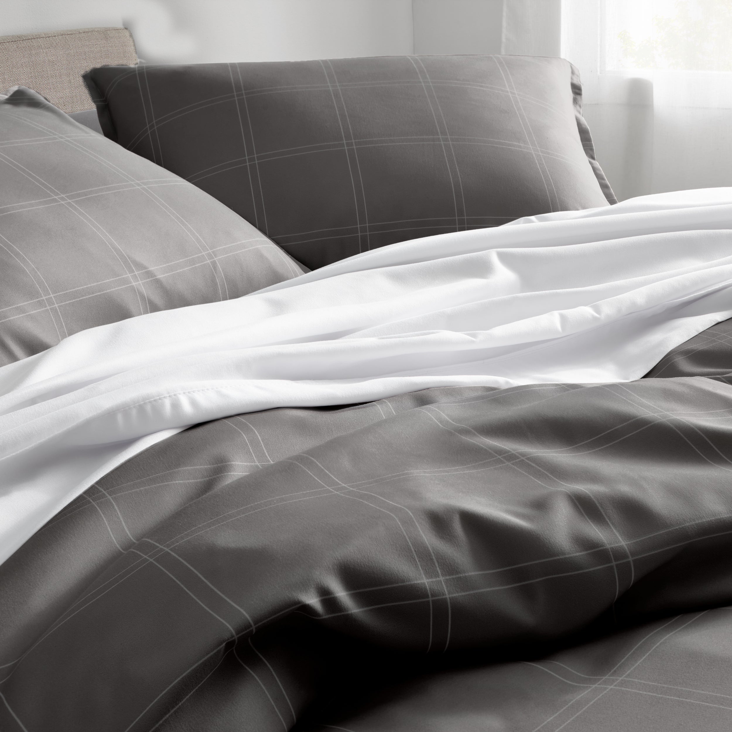 Gray and white plaid bedding set on a bed with pillows.