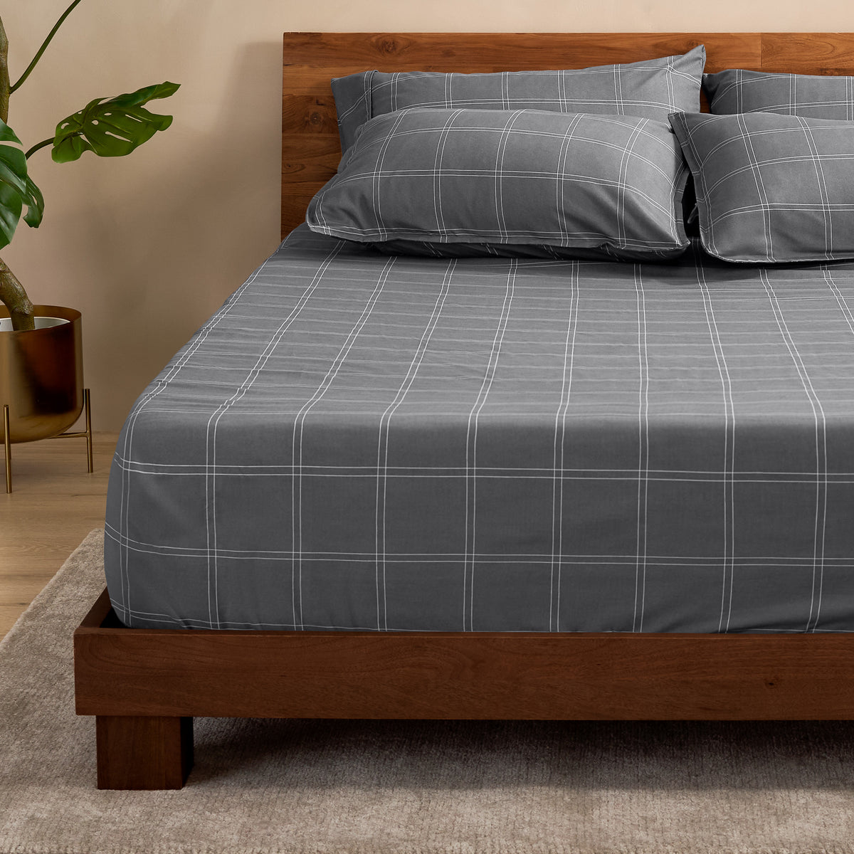 Bed with a fitted sheet with a plant next to it
