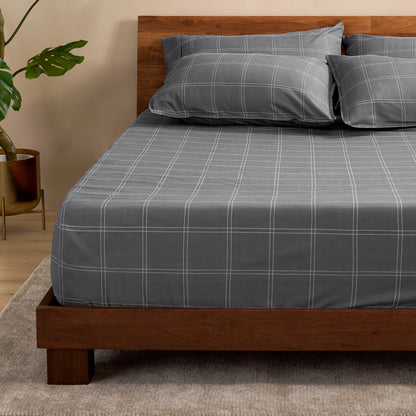 Bed with a fitted sheet with a plant next to it