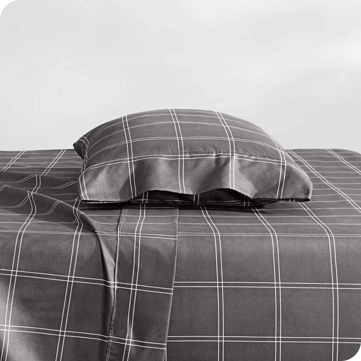 Two pillows with pillowcases on them stacked on a bed