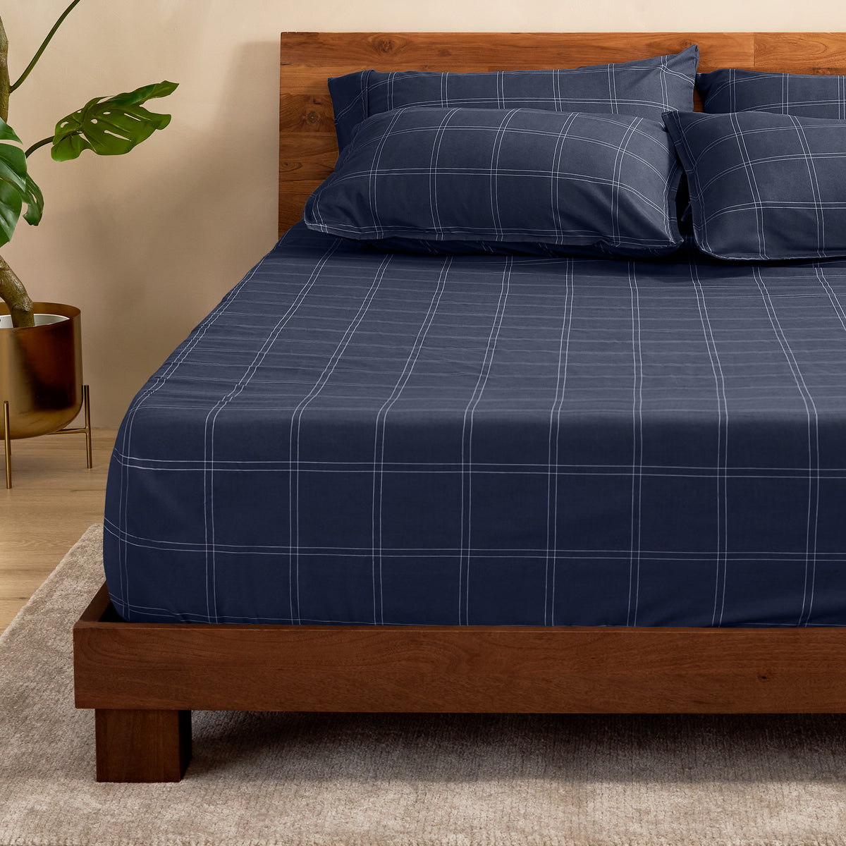 Bed with a fitted sheet with a plant next to it