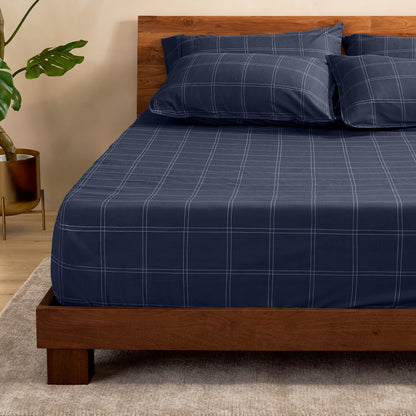 Bed with a fitted sheet with a plant next to it