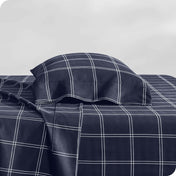 Two pillows with pillowcases on them stacked on a bed