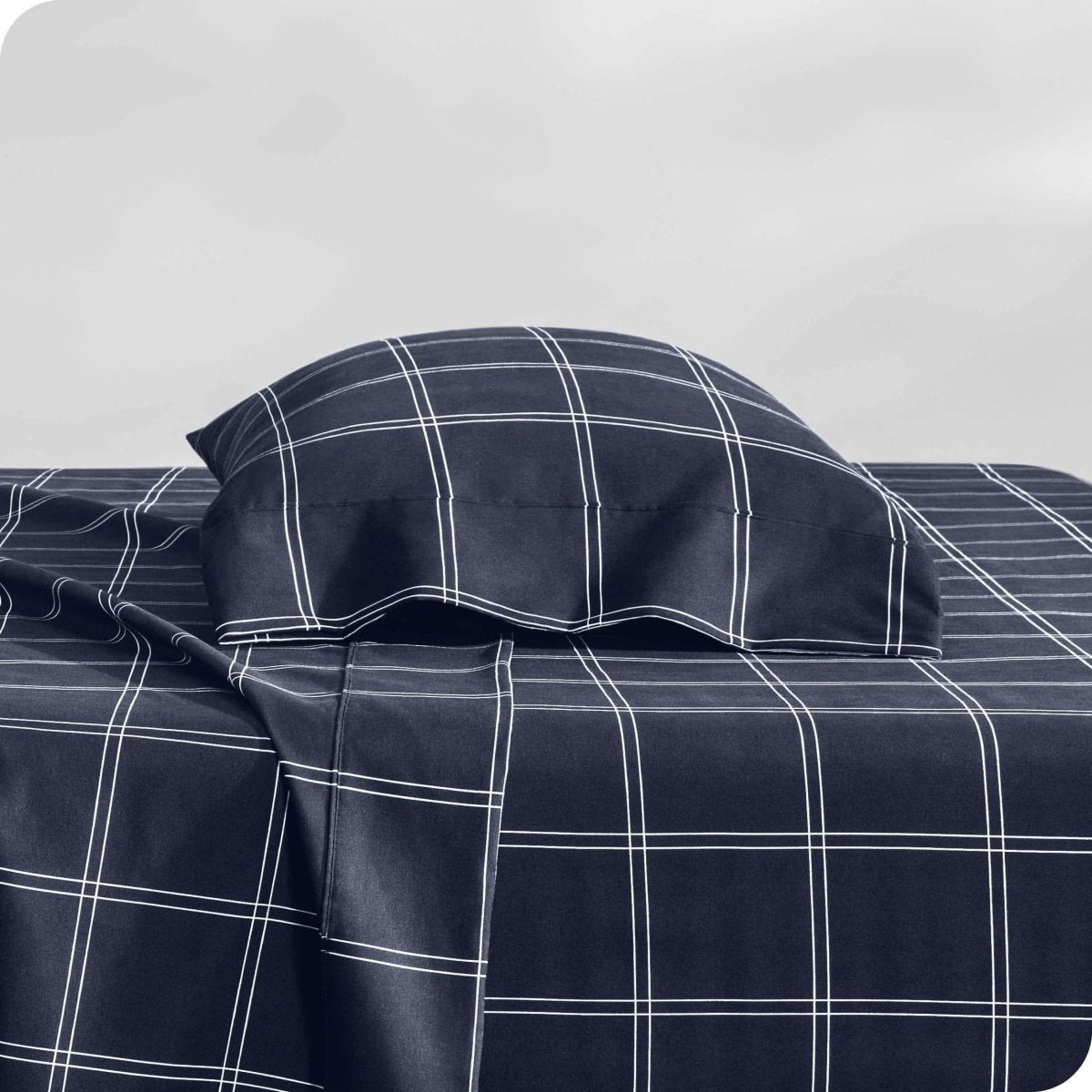 Two pillows with pillowcases on them stacked on a bed