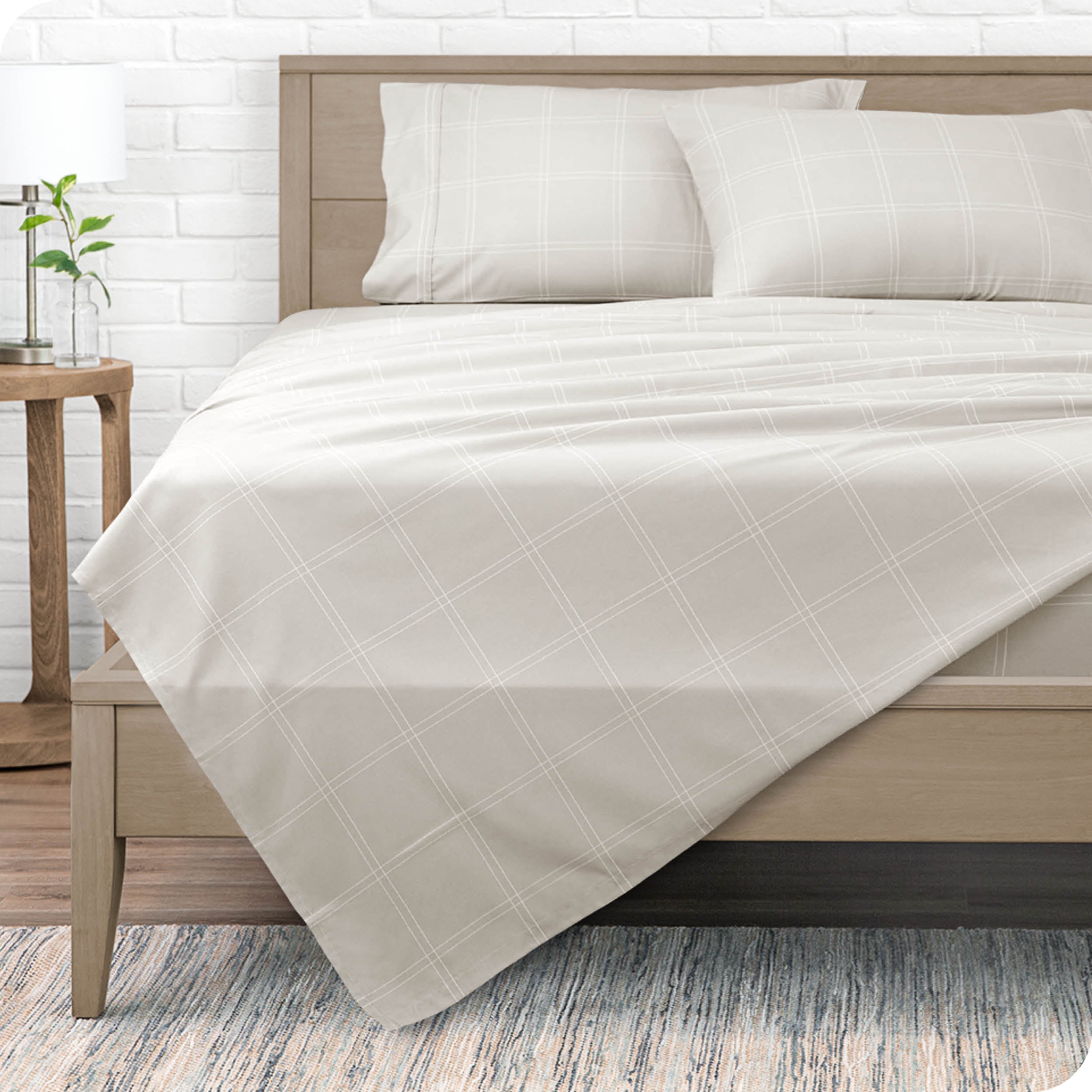 A modern bed with a microfiber sheet set on it.