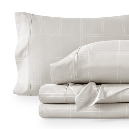 Set of gray checkered bedding including a pillow and two folded sheets on a white background