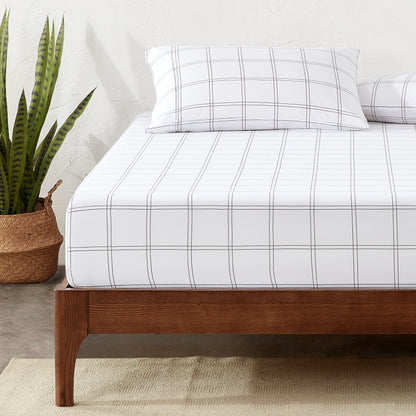 Bed with a fitted sheet with a plant next to it