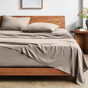 Bed with washed sheets and wooden headboard in a room setting.