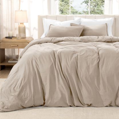 Washed duvet set on a bed in a bright bedroom with a lamp and window.