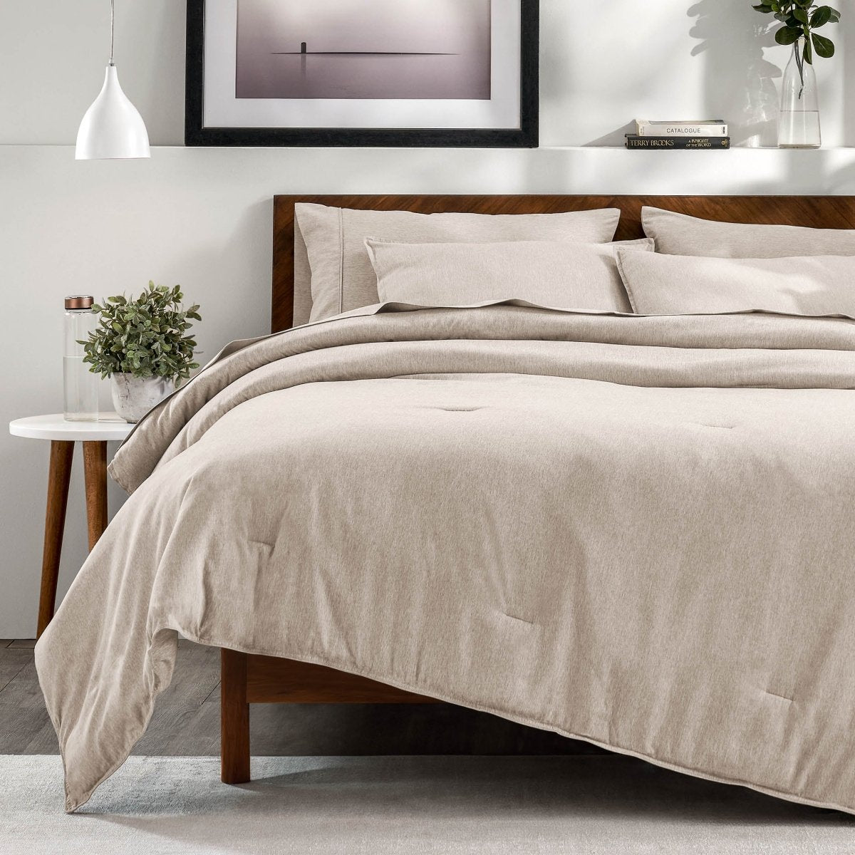 A bedroom with a side table, decor and a neatly made bed