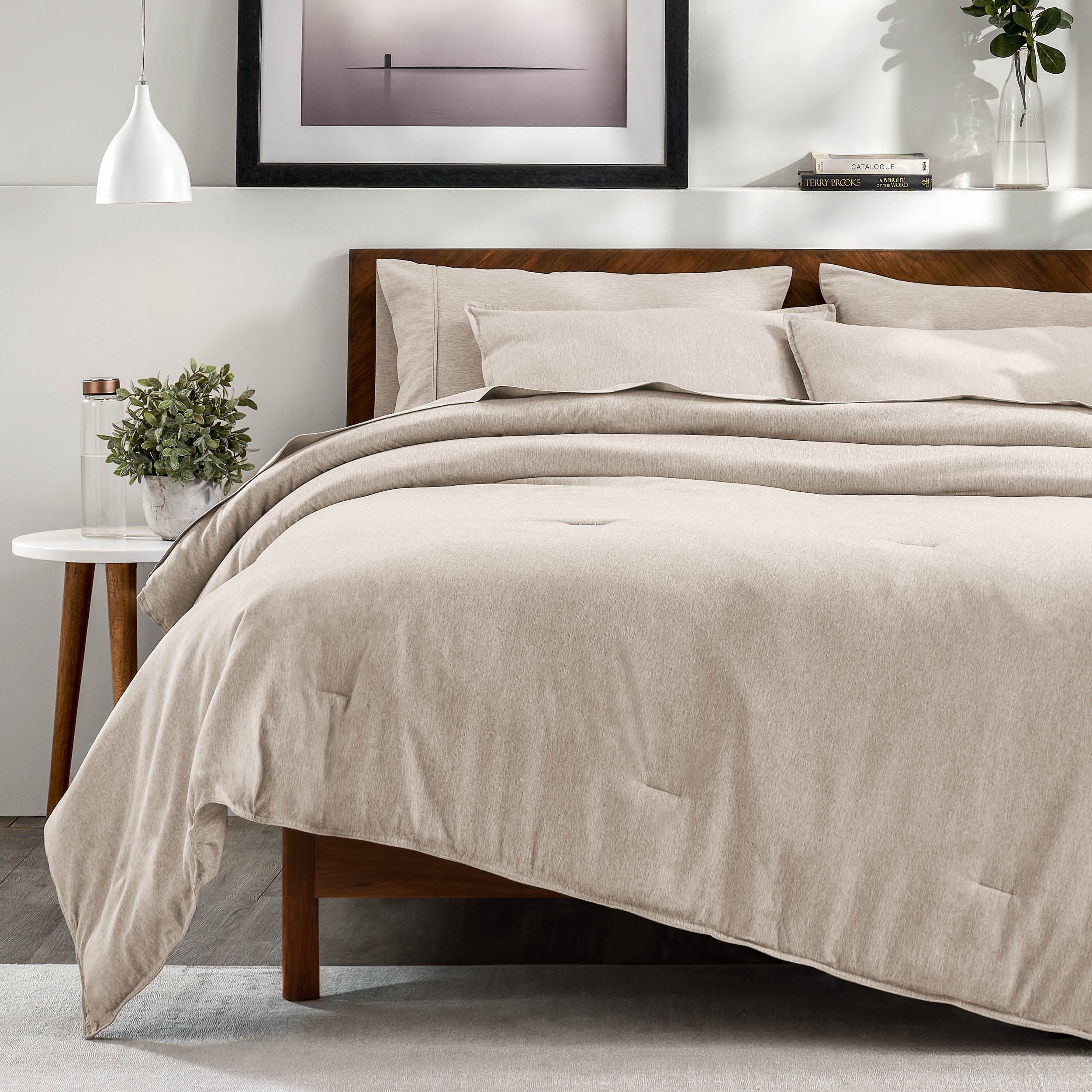 A bedroom with a side table, decor and a neatly made bed