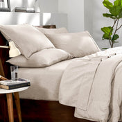 Bedding set on a bed in a bedroom with a side table and lamp.