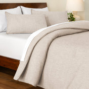 Track stitch comforter on a bed with white pillows and a wooden headboard.